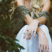 A blonde woman sitting on a rock with her hands on her hips.