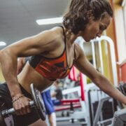 A woman lifting dumbbells in a gym.