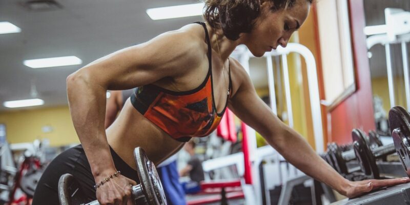 A woman lifting dumbbells in a gym.