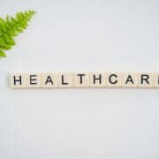 The word healthcare is written in scrabble letters on a white background with a fern leaf.