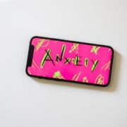 A pink and green phone case with the word anxiety on it.