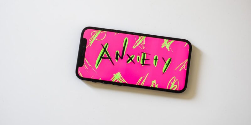 A pink and green phone case with the word anxiety on it.