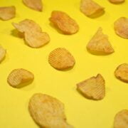 A group of potato chips on a yellow surface.