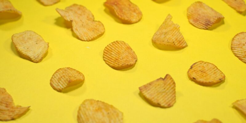 A group of potato chips on a yellow surface.