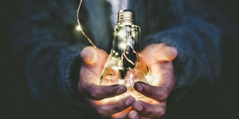 A person holding a light bulb in their hands.