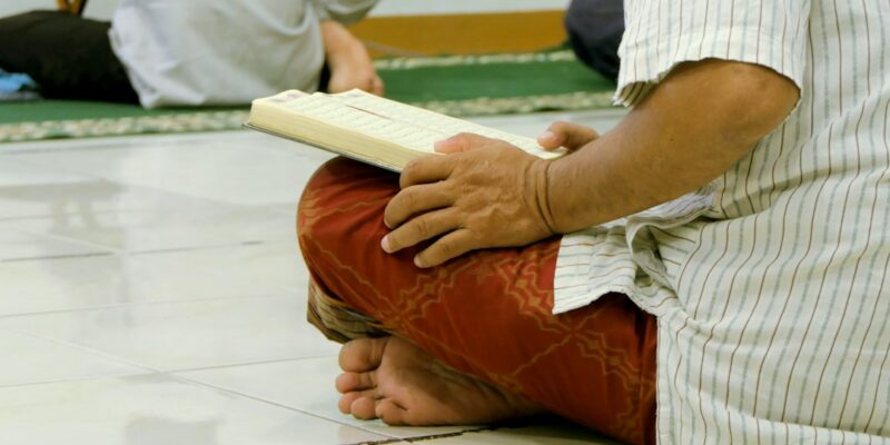 A man sitting on the floor reading a book.