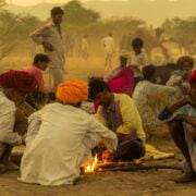 A group of people sitting around a campfire in the desert.