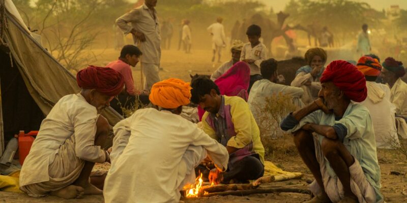 A group of people sitting around a campfire in the desert.