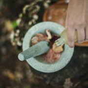 A person pouring a liquid into a mortar.