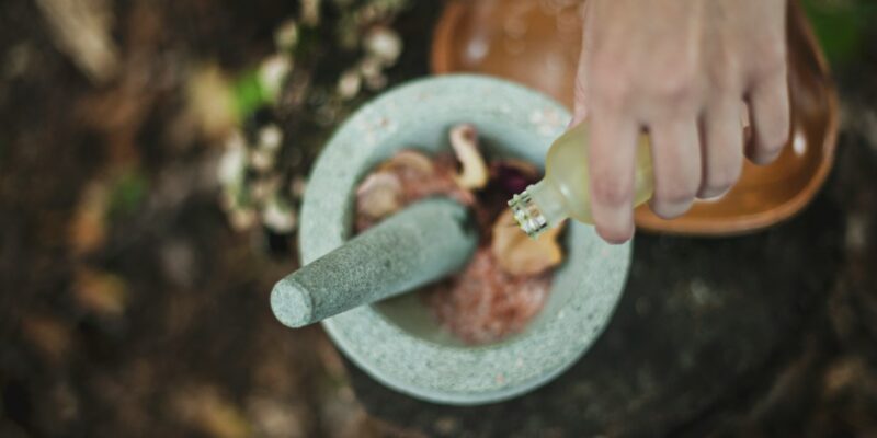 A person pouring a liquid into a mortar.