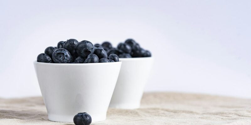 A couple of white bowls filled with blueberries.