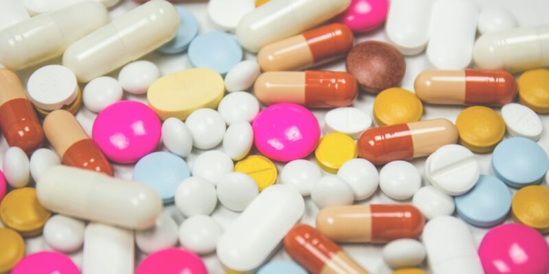 A pile of pills and capsules on a white surface.