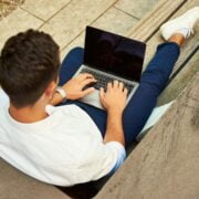 A man sitting on a bench using a laptop.