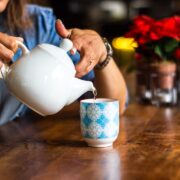 A person pouring a tea into a cup.