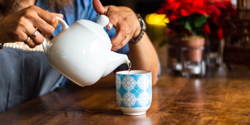 A person pouring a tea into a cup.