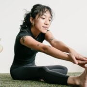 A woman sitting on the floor stretching her legs.