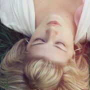 A woman laying in the grass with her eyes closed.