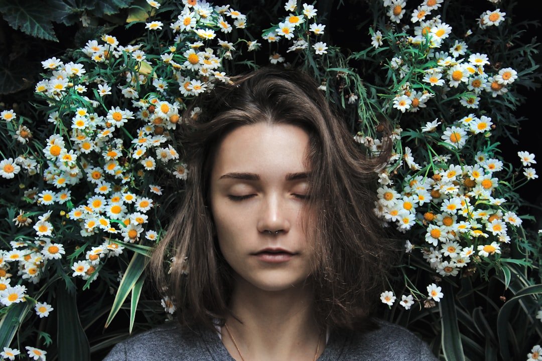 A woman with her eyes closed surrounded by flowers.