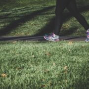 A woman is walking on the grass in a pair of running shoes.