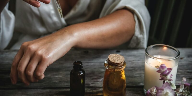 A woman is using essential oils on a wooden table.