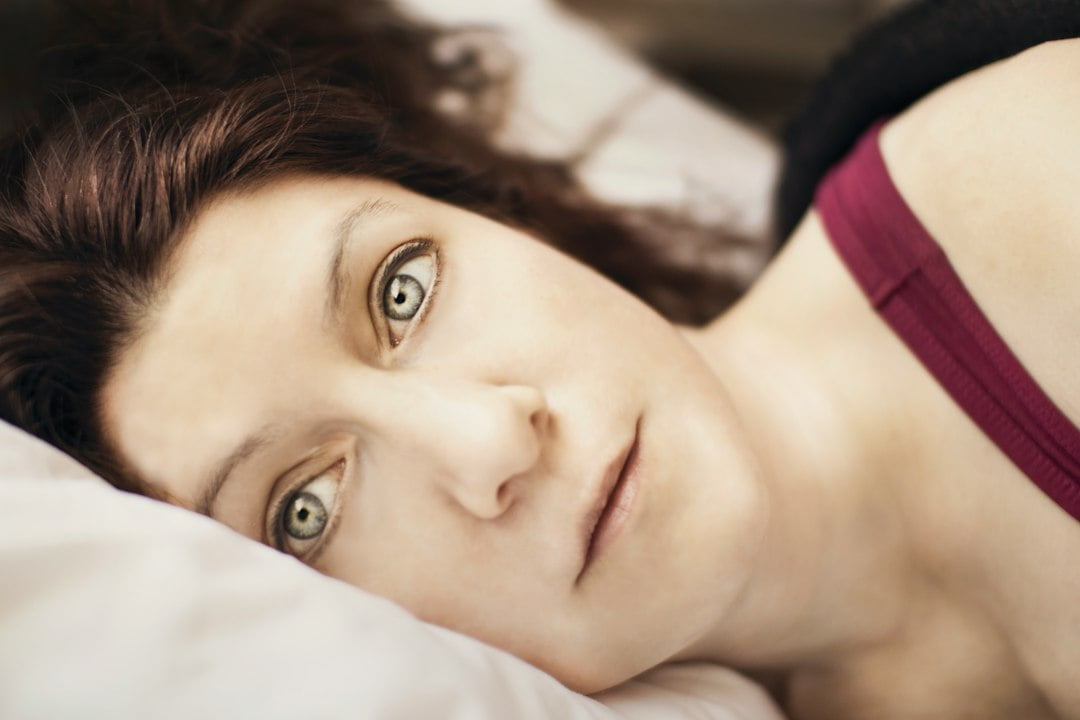 A woman laying in bed with her eyes closed.