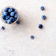 Blueberries in a bowl on a white surface.