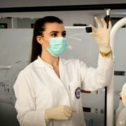 A woman wearing a lab coat and gloves in a dental office.