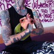 A person with tattoos sitting in a yoga pose.