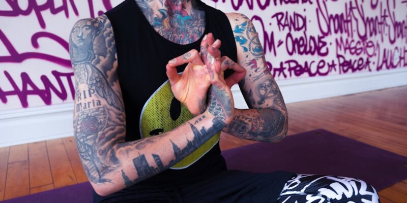 A person with tattoos sitting in a yoga pose.