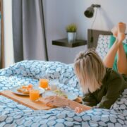 A woman lying in bed with food on a tray.