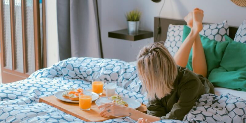 A woman lying in bed with food on a tray.