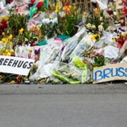 A group of people stand in front of a bunch of flowers in front of a building in brussels, brussels.