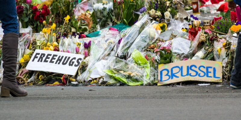 A group of people stand in front of a bunch of flowers in front of a building in brussels, brussels.