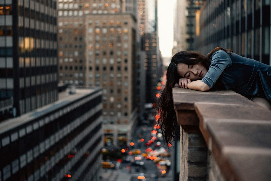 A woman is leaning on a ledge in a city.