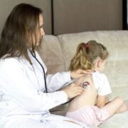 A woman using a stethoscope to listen to a child's heart.