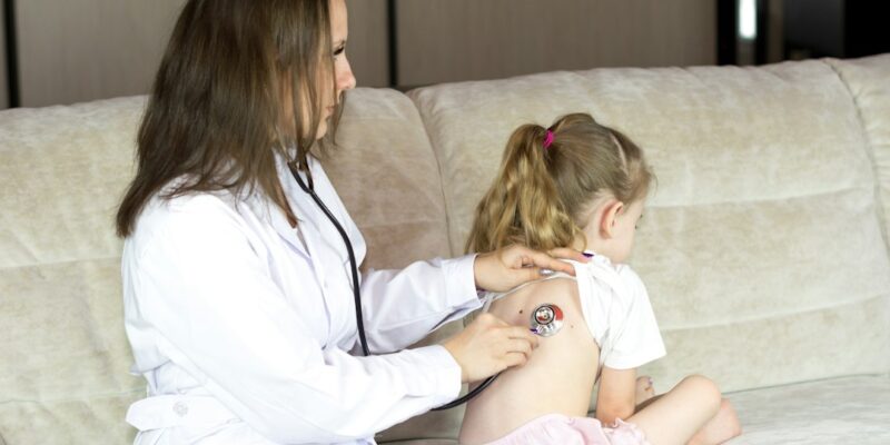 A woman using a stethoscope to listen to a child's heart.