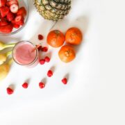 A group of fruits and a smoothie on a white table.