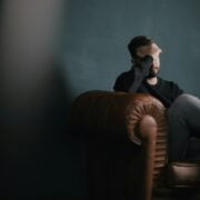 A man sitting on a leather chair in a dark room.