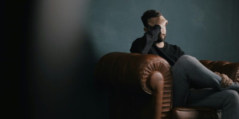 A man sitting on a leather chair in a dark room.