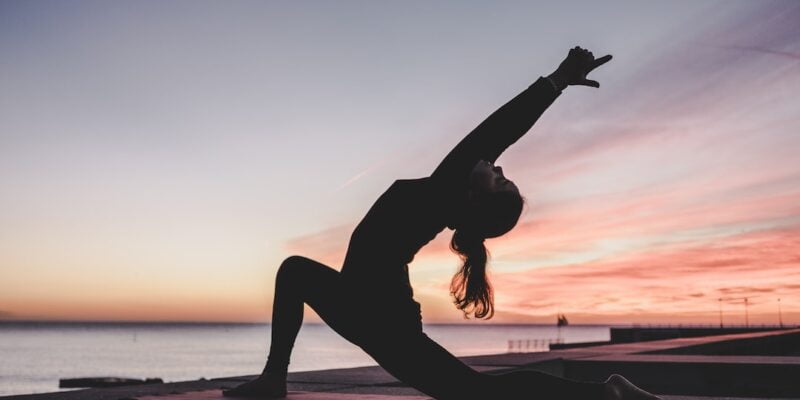 A woman doing yoga on a rooftop.