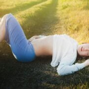 A young woman laying on the ground in a field.