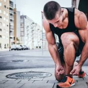 A man tying his shoes on the sidewalk.