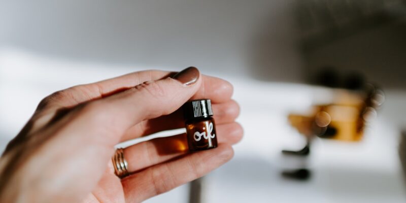 A hand holding a small bottle of oil.