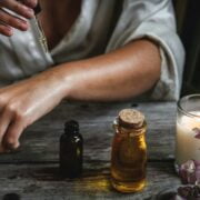A woman is using essential oils on a wooden table.