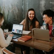 A group of people sitting at a table with laptops.