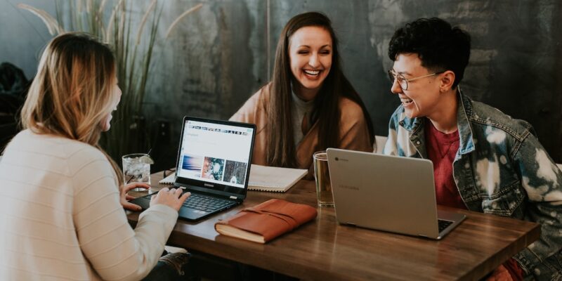 A group of people sitting at a table with laptops.