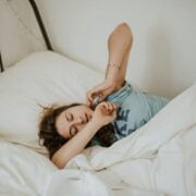 A woman laying in bed with her arms stretched out.