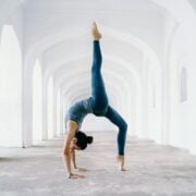 A woman doing a handstand in an empty hallway.