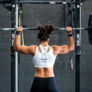 A woman lifting a barbell in a gym.