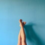 A woman's legs against a blue wall.